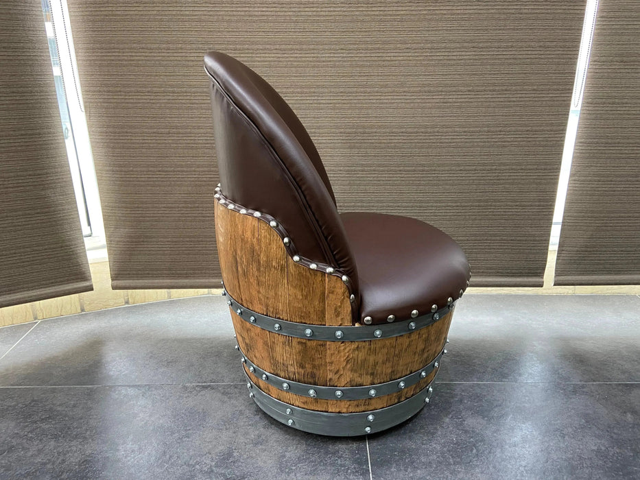 Chair made from a wooden barrel with brown leather seat on a dark floor.
