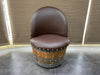 Brown leather chair on a wooden barrel base in a room with curtains.