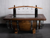 Wooden barrel table with wine bottles and glasses on a tiled floor.