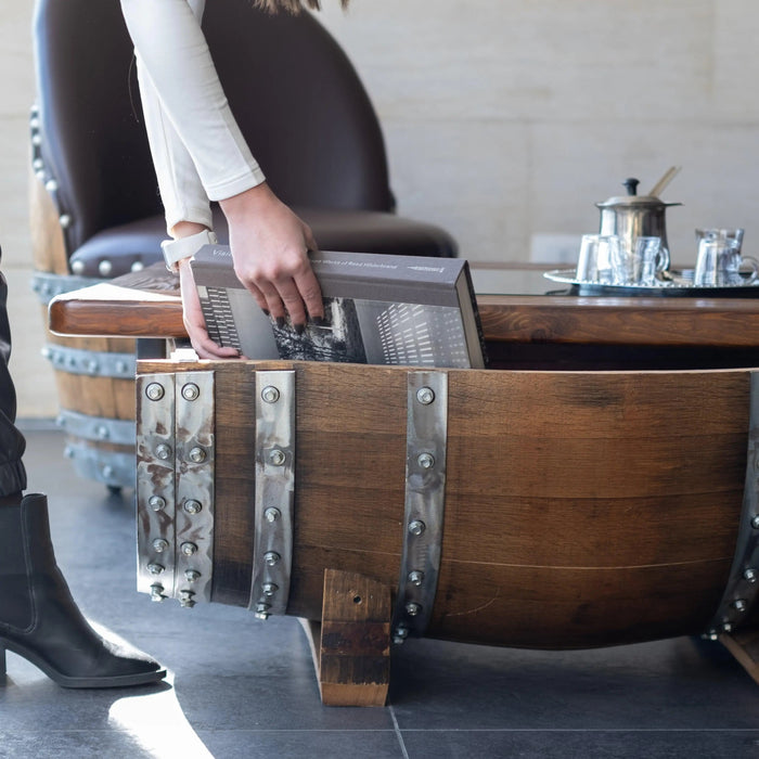 Wooden barrel with metal accents on a floor, person partially visible