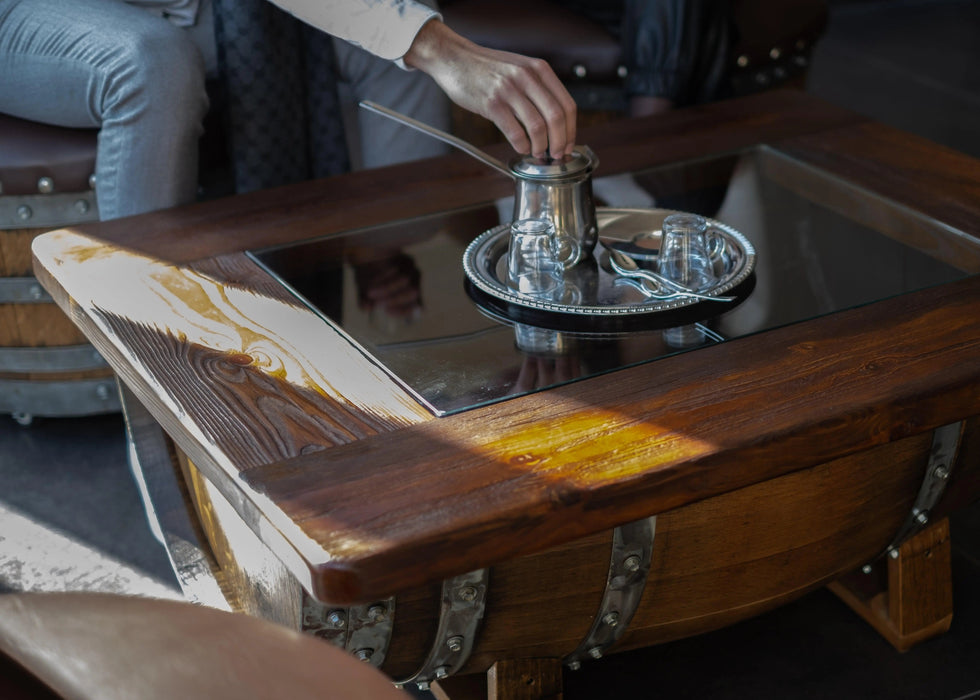Person using a coffee press on a wooden table with a blurred background