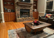 Living room with stone fireplace, wooden coffee table, and decorative items.