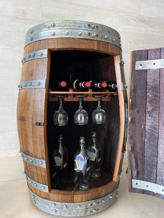 Wooden barrel with wine bottles and glasses inside, against a light background
