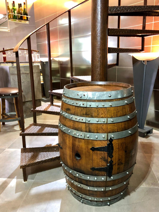 Wooden barrel with metal bands in a room with chairs and a lamp.